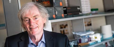 Dr. Pieter Cullis in front of shelves in his lab