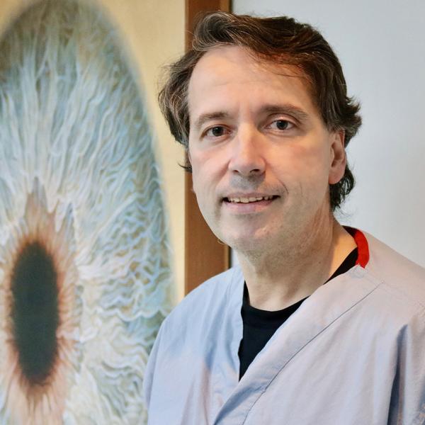 Dr. Navajas standing next to a large image of an eye